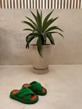 Sandalias de plataforma con diseño de tiras cruzadas acolchadas en color verde y plantilla en color naranja.