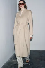 Abrigo largo de corte minimalista confeccionado en mezcla de lana, con diseño de solapas integradas, manga larga y cinturón ajustable del mismo tejido.