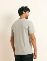 Remera básica de algodón color beige, de manga corta, con cuello redondo y un pequeño detalle bordado en el pecho.