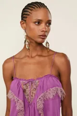Vestido largo lila de viscosa con tirantes finos, escote recto con lazo ajustable, silueta fluida, tajo lateral en la falda y detalles de encaje en el canesú del busto.