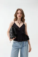 Musculosa negra con tirantes finos, escote en V cruzado con detalle de volados y diseño peplum en la parte inferior.
