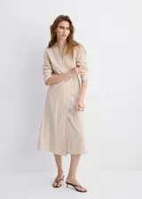 Vestido midi cruzado beige con sutiles rayas verticales oscuras, cuello camisero con solapa, mangas largas y cierre delantero cruzado.