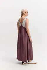 Vestido largo de silueta amplia y caída fluida, sin mangas, con escote en V y recorte bajo el busto. Combina un cuerpo superior beige con ribetes oscuros y una falda larga en color verde militar.