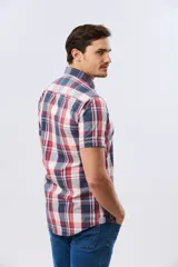 Camisa de manga corta con estampado de cuadros en tonos celestes, azules, blancos y verdes, con cierre frontal de botones y bolsillo ojal en el pecho.
