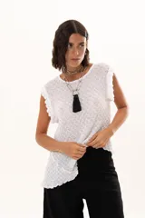 Blusa sin mangas de silueta relajada, confeccionada en tejido tipo encaje con textura. Presenta volantes sutiles en los hombros y un diseño con terminación asimétrica en pico hacia un lateral.