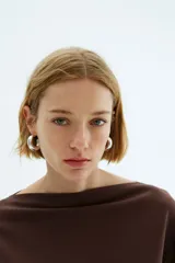 Top de manga larga color marrón oscuro, confeccionado en tejido de punto suave, con escote bote y mangas amplias.