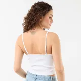 Top blanco de tirantes finos ajustables, confeccionado en tejido de canalé y diseño al cuerpo.