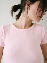 Remera de manga corta color blanco con textura pointelle, corte entallado y cuello redondo con detalle de borde sutilmente ondulado.
