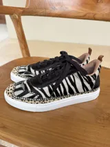 Championes de cuero con diseño de animal print combinado, presentando patrón de cebra en el cuerpo y detalles de leopardo en la puntera. Poseen cordones negros, suela blanca y forro interior en tono nude.