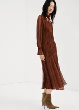 Vestido midi marrón de viscosa transparente, con diseño plisado, cuello alto fruncido y mangas largas abullonadas con puños elásticos. Presenta detalles de costuras fruncidas en la cintura y falda escalonada con vuelo.