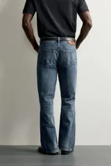 Jeans flare fit de denim negro, tiro medio, ajustados arriba y con botamanga acampanada. Cuentan con cinco bolsillos, lavado efecto gastado y bajo con acabado irregular. Cierre frontal con cremallera y botón.