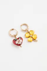 Par de aros tipo argolla con dijes colgantes asimétricos: uno con forma de corazón esmaltado multicolor y otro con forma de trébol de cuatro hojas rojo con centro de cristal.