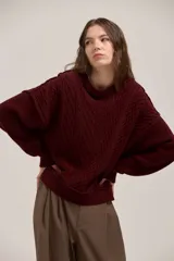 Sweater de punto con diseño de trenzas, cuello redondo y corte holgado. Presenta un estilo clásico con acabado en puños y ruedo acanalados.