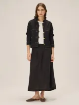 Campera negra de algodón con elastano, corte relajado, cuello alto y cierre frontal asimétrico con botones metálicos dorados y presillas decorativas. Presenta costuras pespunteadas en contraste.