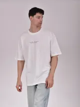Remera color verde petroleo, de manga corta y corte oversize, con estampa en el pecho izquierdo que dice 'Noble Origins' junto a un diseño floral.