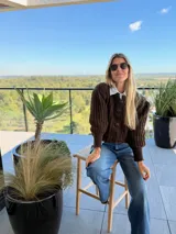 Saco de punto color chocolate con diseño de tejido acanalado, cuello redondo, cierre frontal con botones grandes y mangas globo con puños ajustados.