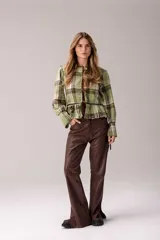 Blusa de tartán con diseño versátil, confeccionada en tela escocesa con detalles en cuero de oveja. Presenta cuello alto con forro de piel sintética, mangas largas con puños de cuero y piel, y un ruedo tableado con ajuste de cinturón de cuero en la cintura.