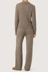 Conjunto de dos piezas compuesto por un sweater de punto trenzado con cuello polo y un pantalón de corte recto, ambos confeccionados en tejido de punto suave color marrón.