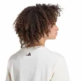 Remera de algodón beige de corte clásico, con mangas cortas y cuello redondo. Presenta un estampado frontal que combina el texto "Adidas" y "Farm Rio" en color marrón con un gran ramo de flores coloridas en el centro.