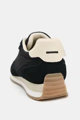Zapatilla deportiva tipo running con diseño de paneles en contraste. Presenta cuerpo en color negro con refuerzos de gamuza sintética, detalle de pespuntes, talón en color crema y suela dentada bicolor.