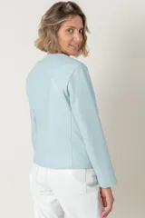 Campera de cuero ovino color celeste claro, estilo chaqueta corta, con cuello redondo y cierre frontal de botones. Presenta bolsillos delanteros con solapa curva.