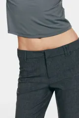 Pantalón sastrero gris oscuro de tiro alto, con corte acampanado, trabillas para cinturón y cierre frontal con cremallera y gancho oculto.