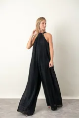 Enterito largo de lurex plisado color negro, con escote halter y corte amplio en las piernas. Incluye un cinturón metálico decorativo en la cintura.