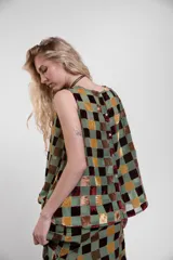 Musculosa de cuello redondo, confeccionada en tejido transparente con diseño de cuadrados de terciopelo a tres colores, con cierre de botones en la espalda.