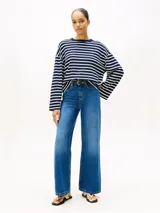 Jean de Tommy Hilfiger confeccionado en denim rígido, con corte de pierna ancha y talle alto. Presenta un diseño clásico de cinco bolsillos, cierre de cremallera con botón y un sutil efecto desteñido en muslos y rodillas.