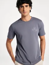 Remera blanca de manga corta con cuello redondo y estampa frontal con diseño gráfico de club de pesca en tonos azul y rojo.
