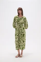 Vestido midi holgado con estampado de hojas en tonos verde y beige, cuello redondo con abertura en V y botones, y mangas 3/4 abullonadas.