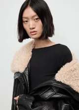 Remera negra de manga larga con cuello barco, confeccionada en tejido elástico y entallado.