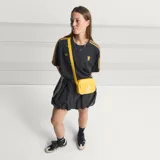 Camiseta de fútbol Adidas del Manchester United, modelo Terrace Icons. Diseño negro con sutiles rayas verticales moradas, franjas amarillas en los hombros y detalles bordados en dorado, incluyendo el trébol de Adidas y el escudo clásico del club.