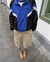 Campera deportiva de diseño colorblock en tonos azul, negro y blanco, con cierre frontal y cuello alto. Presenta detalles de franjas y un pequeño estampado en el pecho con la inscripción "Uruguay Run Club".