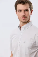 Camisa de manga corta con microcuadros en tonos celestes y blancos, calce slim, cuello con botones y bolsillo frontal con logo bordado.