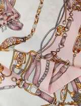 Pañuelo cuadrado de satén con estampado de cadenas y motivos ecuestres en tonos azul, blanco y dorado.