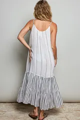 Vestido largo sin mangas de color blanco con rayas verticales oscuras, corte holgado y diseño con volantes en la parte inferior.