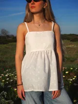 Blusa blanca de broderie con tirantes finos, escote recto y corte fluido evase.