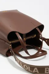 Bolso de mano tipo tote de Bimba y Lola, color marrón, confeccionado en piel reconstituida. Presenta doble asa de mano, asa de tejido ajustable con logo de la marca, cierre de botón de presión y logo metálico frontal.