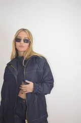 Campera de jean azul con cierre dorado, cuello clásico, mangas largas con puños elásticos y costuras blancas a contraste.