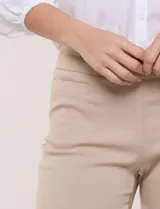 Pantalón de gabardina elastizada color beige, de tiro medio y calce slim. Cuenta con diseño pull-on sin cierres ni botones, cintura ancha, bolsillos delanteros simulados y bolsillos traseros ojal.