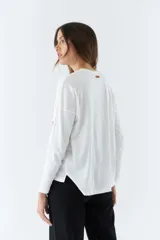 Remera blanca de algodón con mangas largas, cuello redondo y estampado con la frase 'look deeper always true art'.