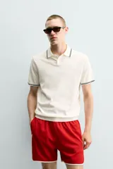 Polo de punto tejido en algodón, de corte regular fit. Presenta cuello solapa con cierre frontal de botones y manga corta, con acabados en rib y detalles de bandas a contraste en cuello y puños.