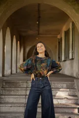 Blusa de lino con estampado artístico en tonos tierra, verdes y azules. Presenta un corte holgado con mangas abullonadas, puños elásticos y un cordón ajustable en el ruedo frontal para entallar la cintura.