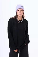 Buzo tejido de punto con diseño de trenzas, color negro, de corte holgado, cuello redondo y mangas largas.