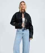 Pantalón de jean estilo wide leg con cintura media, cierre frontal con botón y cremallera, bolsillos funcionales y diseño de pierna amplia con recorte transversal.