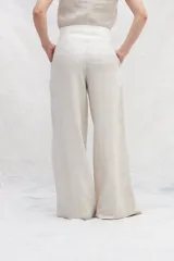 Pantalón de lino color beige y blanco, de corte amplio a la cintura y con bolsillos laterales.