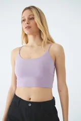 Top corto de dama con escote redondo y tiras cruzadas en la espalda. Presenta un diseño ajustado al cuerpo y cuenta con una grifa metálica decorativa.