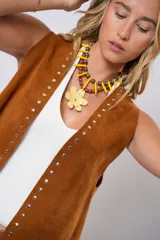 Chaleco marrón de cuero descarne con terminación en picos, tachas metálicas y flecos en la espalda.