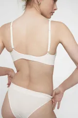 Soutien tipo bralette color beige, sin costuras y sin aro, con copas removibles. Confeccionado en microfibra, tiene breteles regulables y broche doble en la espalda con tres medidas.